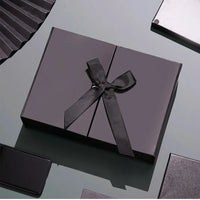 Caixa dobrável com fechamento magnético e laço decorativo.