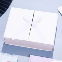 Caixa dobrável com fechamento magnético e laço decorativo.